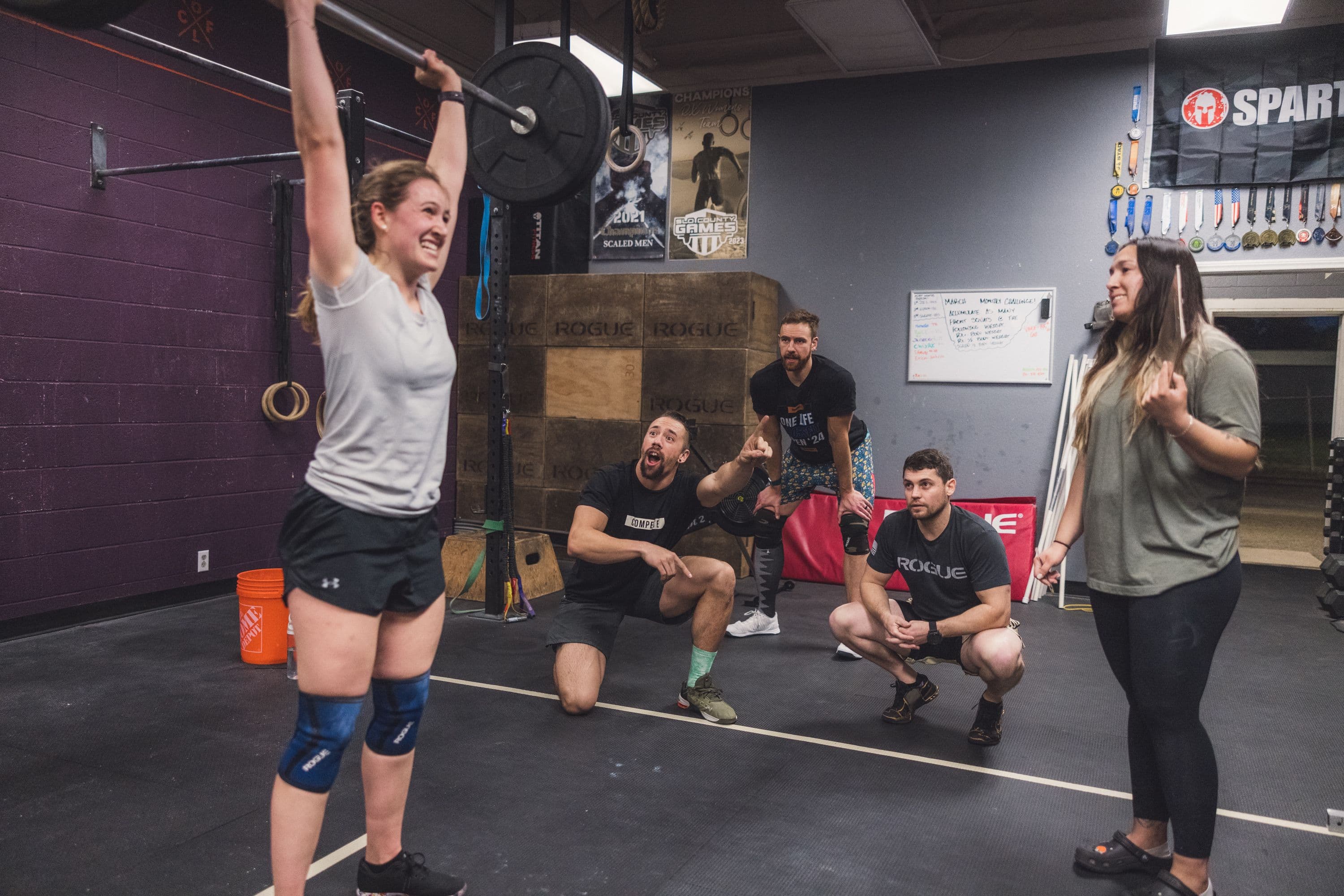 One Life CrossFit athlete finishing an overhead lift while the class looks on